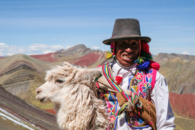 Portrait of man wearing hat against mountains against sky