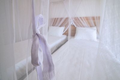 View of bed seen through white curtain