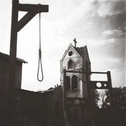 Low angle view of noose by old church against sky