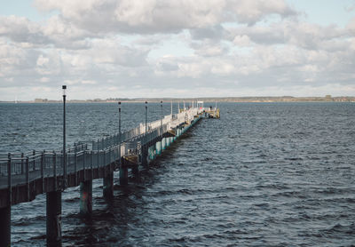 Wooden posts in sea against sky