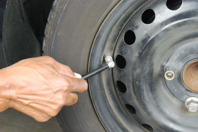 Cropped image of hand checking car tire with gauge