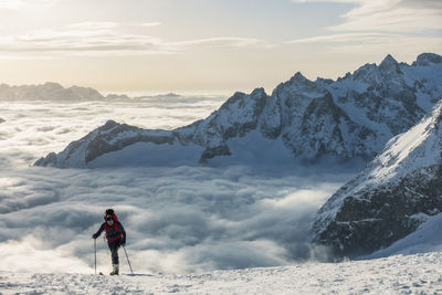 Man standing on snowcapped mountain against sky