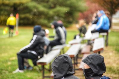 Rear view of people sitting on bench in park