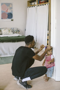 Young man combing hair of daughter at home