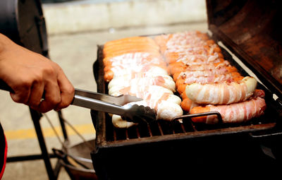 Close-up of person preparing food on barbecue grill