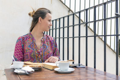 Young woman having toast for breakfast at a bar terrace