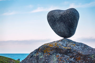 Close-up of heart shape rock by sea against sky