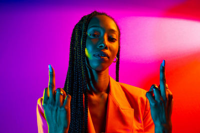 Portrait of young woman holding camera over colored background