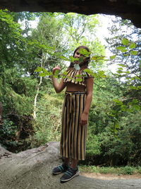 Man standing by tree in forest