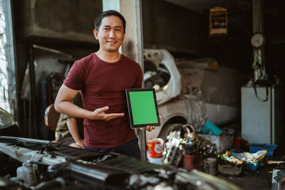 Portrait of young man using digital tablet while standing in workshop