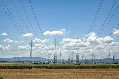 Electricity pylon on field against sky