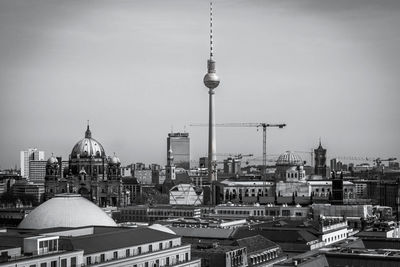 Communications tower in city against sky