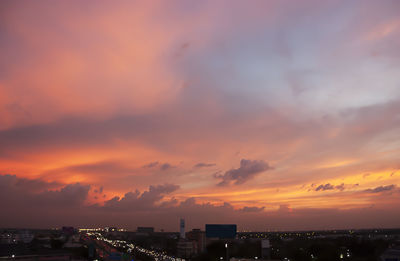 Cityscape against dramatic sky during sunset