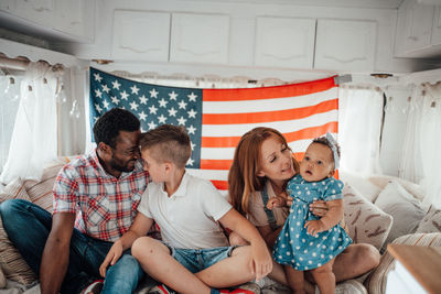 Cheerful family sitting against american flag