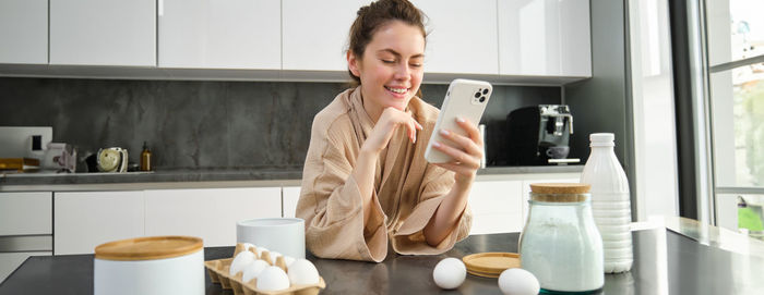 Portrait of young woman standing in kitchen