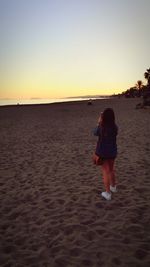 Rear view of man walking on beach against clear sky