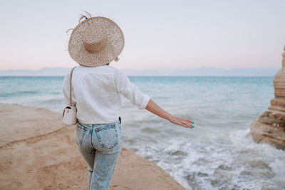 Rear view of woman standing on beach against sky