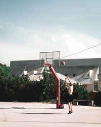 Man playing with basketball hoop against sky