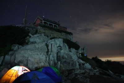 Low angle view of house on mountain against cloudy sky at night