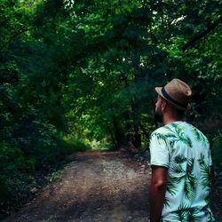 Rear view of man standing by trees in forest