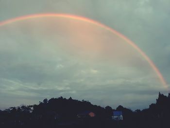 Low angle view of rainbow over buildings against sky