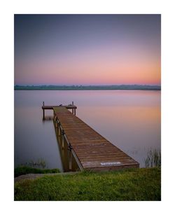 Pier over lake against sky during sunset