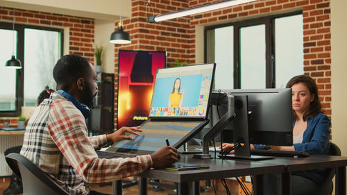 Rear view of man using laptop at office