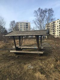 Abandoned building by trees on field against sky