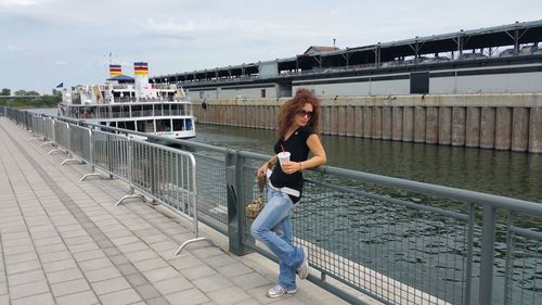 Full length of woman leaning on railing by canal