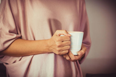 Midsection of woman holding coffee cup