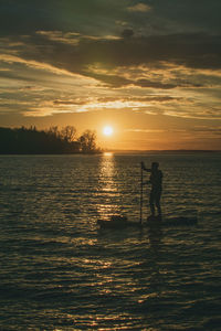 Silhouette man standing by sea against sky during sunset