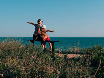 Full length of young woman at sea shore against sky