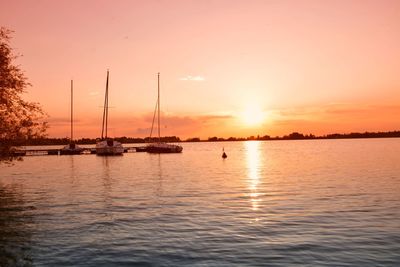 Sailboats in sea against sky during sunset