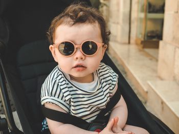 Portrait of cute baby girl sitting in stroller