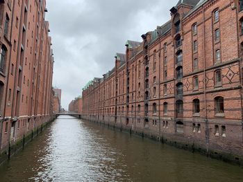 Canal amidst buildings in city against sky