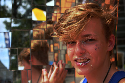 Close-up portrait of teenage boy with glitter on face