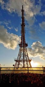 Low angle view of communications tower on field against sky