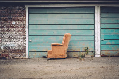 Abandoned armchair in front of wall on street