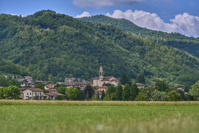 Scenic view of field by buildings against sky