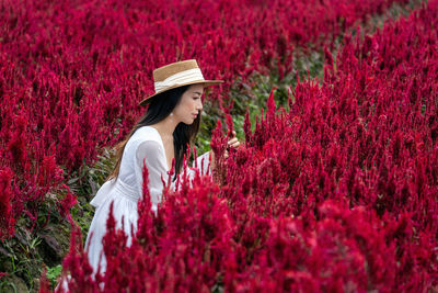 Close-up of woman with red flowers in garden