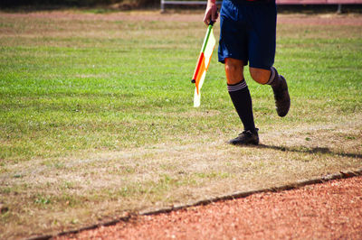 Low section of soccer player with flag running on field