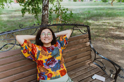 Joyful young woman enjoying a peaceful moment on a park bench with music.