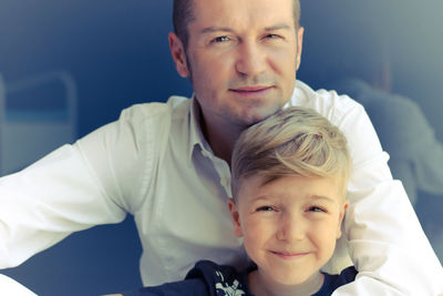 Portrait of happy father and son against wall