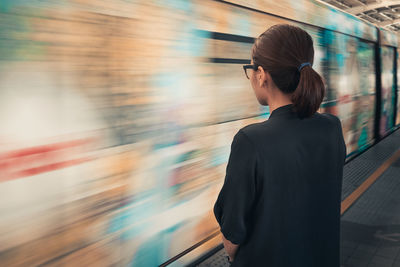 Rear view of woman standing at railroad station