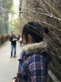 Side view of woman standing by dried plant