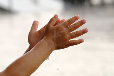 Close-up of woman hand with wet leaf against blurred background