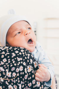 Infant boy yawning on her mother's shoulder