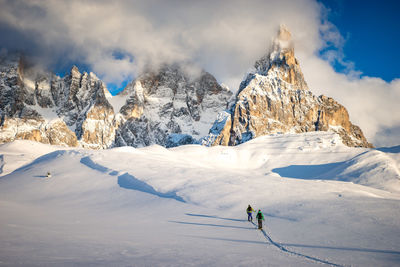 People skiing on snowcapped mountain against sky