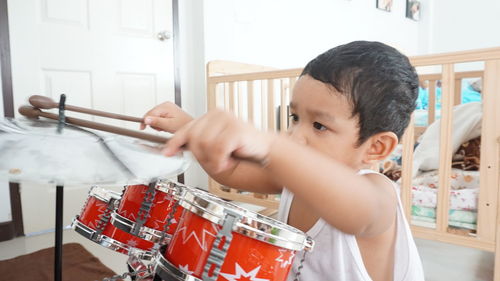 Cute baby boy playing drum kit at home