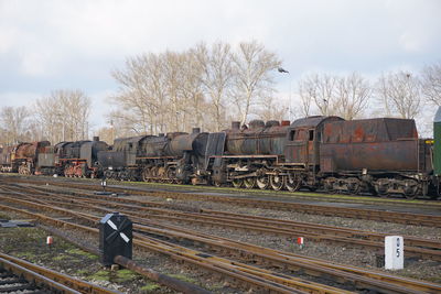 Metallic rusty train on railroad track against bare trees